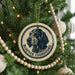A Christmas tree decorated with ornaments, including a circular ornament with a black and white illustration of a blue and white dog and the text "BLUE TICKET COONHOUND".