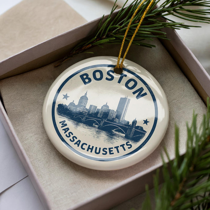 A circular ornament with the text "BOSTON MASSACHUSETTS" and a cityscape illustration, hanging from a string.
