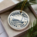 A decorative ornament in a box, featuring a lighthouse and the text "VIRGINIA BEACH USA".