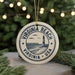 A round ornament with the text "VIRGINIA BEACH USA" and a lighthouse image, hanging on a string.