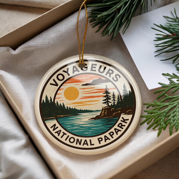 A circular ornament with the text "VOYAGUEURS NATIONAL PAPARK" and an illustration of a sunset over a lake surrounded by pine trees.