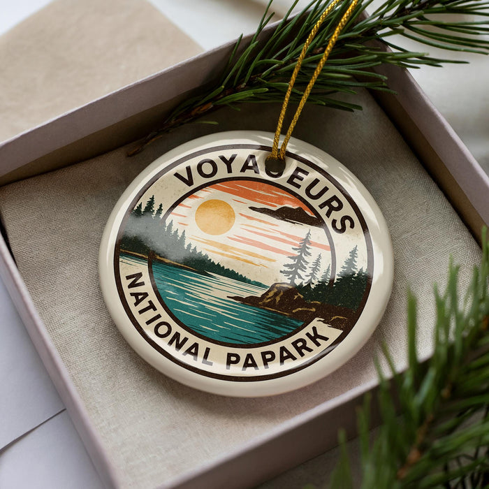 A circular ornament with the text "VOYAGE EURS NATIONAL PAPARK" and a landscape design, placed in a box with pine branches.