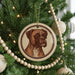 A Christmas tree decorated with ornaments, including a circular ornament featuring a brown dog's face.