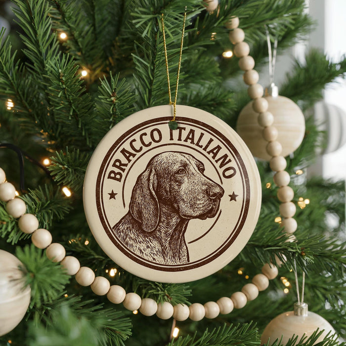 A Christmas tree decorated with ornaments, including a circular ornament with a dog's head and the text "BRACCO ITALIANO" printed on it.
