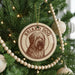 A Christmas tree decorated with ornaments, including a circular ornament with a brown and white image of a dog and the text "BRIARD DOG" on it.