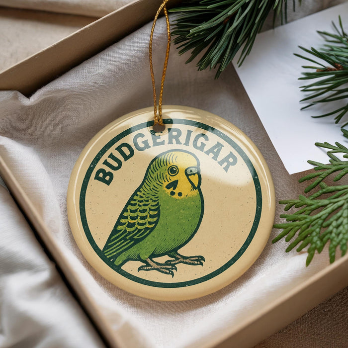 A round ornament with a green parakeet design, hanging from a string, placed inside a box with pine branches.