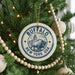 A circular ornament on a Christmas tree, featuring a buffalo and the text "BUFFALO NEW YORK USA".