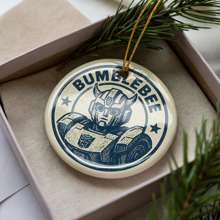 A circular ornament with the text "BUMBLEBEE" and an illustration of a robot or character is displayed in a box, surrounded by pine branches.
