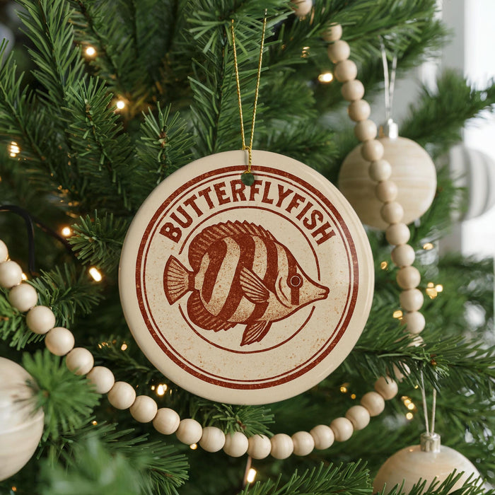 A Christmas tree decorated with ornaments, including a circular ornament with a butterflyfish design and a string of wooden beads.