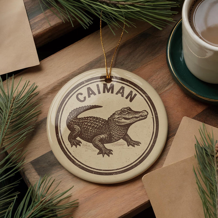 A circular ornament featuring a cartoon alligator is displayed on a wooden surface, surrounded by pine branches and a cup of coffee.