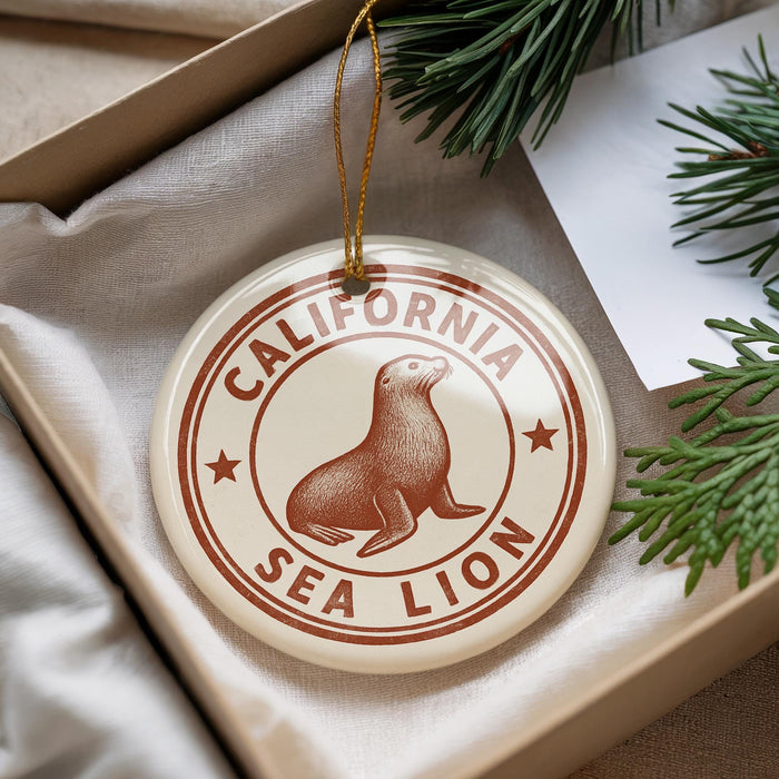 A round ornament with a seal and the text "CALIFORNIA SEA LION" is displayed in a box, surrounded by pine branches.