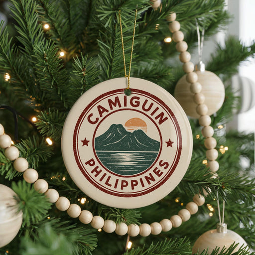 A Christmas tree decorated with ornaments, including a circular ornament with the text "CAMIGUIN PHILIPPINES" and a mountain landscape design.