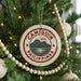 A Christmas tree decorated with ornaments, including a circular ornament with the text "CAMIGUIN PHILIPPINES" and a mountain landscape design.