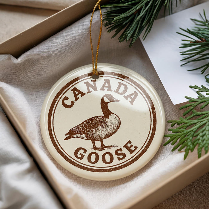 A circular ornament with the text "CANADA GOOSE" and a graphic of a goose is displayed in a box with pine branches.