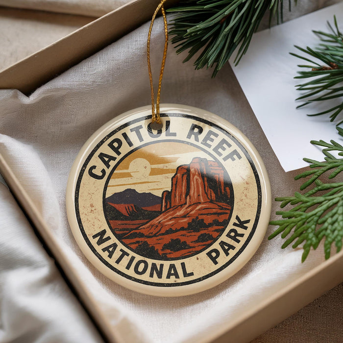 A decorative ornament with the text "CAPITOL REEF NATIONAL PARK" on it, featuring an illustration of a desert landscape with mountains and a sun.