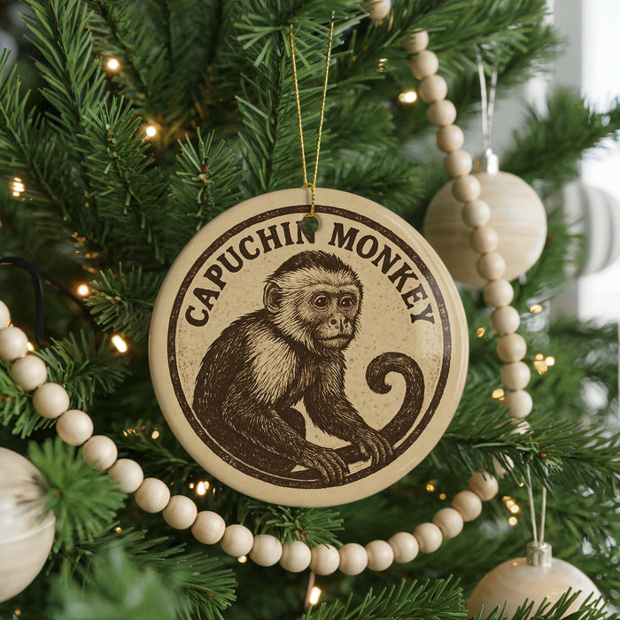A round ornament with a monkey image is hanging on a Christmas tree, surrounded by other ornaments and lights.