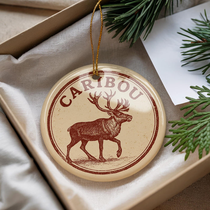 A circular ornament with a deer illustration and the word "CARIBOU" printed on it, hanging from a string.
