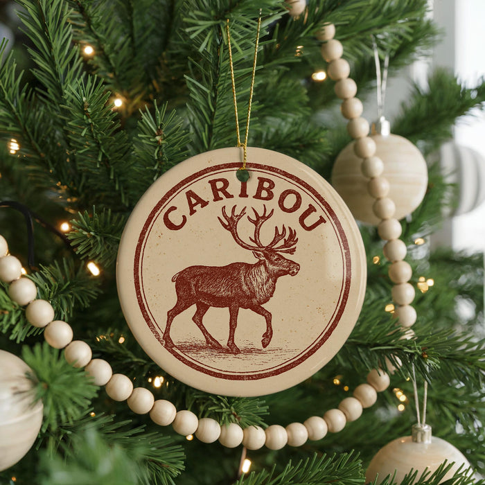 A Christmas tree decorated with ornaments, including a circular ornament with a deer image and the word "CARIBOU" written on it.