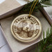 A ceramic ornament in a box, featuring a portrait of a Cavalier King Charles Spaniel dog.