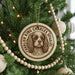 A round ornament with a picture of a Cavalier King Charles Spaniel dog on it, hanging from a Christmas tree.