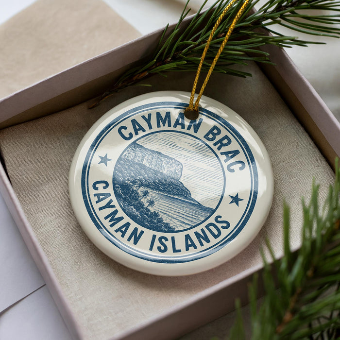 A circular ornament with the text " Cayman Islands" printed on it, surrounded by pine branches.