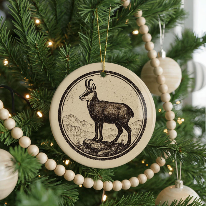 A Christmas tree decorated with ornaments, including a circular ornament featuring a deer standing on a rock.