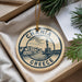 A circular ornament with the text "CHANIA GRECE" and an illustration of a cityscape is displayed in a box, surrounded by pine branches.