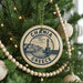 A circular ornament on a Christmas tree, featuring the text "CHANIA GRECE" and an illustration of a lighthouse and buildings.