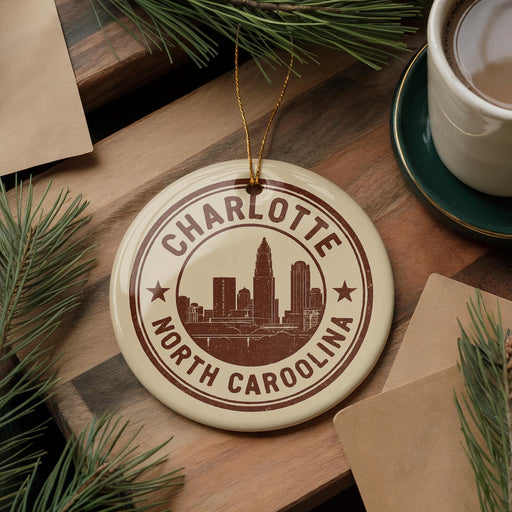 A circular ornament with the text "CHARLOTTE NORTH CAROLINA" and a graphic of a city skyline, hanging on a wooden surface.