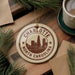 A circular ornament with the text "CHARLOTTE NORTH CAROLINA" and a graphic of a city skyline, hanging on a wooden surface.