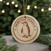 A round ornament with a penguin image and the text "CHINSTRAP PENGUIN" is displayed in front of a Christmas tree with twinkling lights.