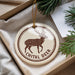 A decorative ornament featuring a deer with antlers, placed in a box with pine branches.