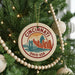 A circular ornament on a Christmas tree, featuring a cityscape and the text "CINCINNATI, OHIO, USA".