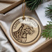 A round ornament featuring a leopard's head, with the text "CLOUDED LEOPARD" printed on it, is displayed in a box with pine branches.