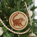 A Christmas tree decorated with ornaments, including a circular ornament featuring a raccoon silhouette.