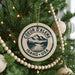 A Christmas tree decorated with ornaments, including a circular ornament with the text "COEUR D'ALENE IDAHO USA" and a mountain landscape design.