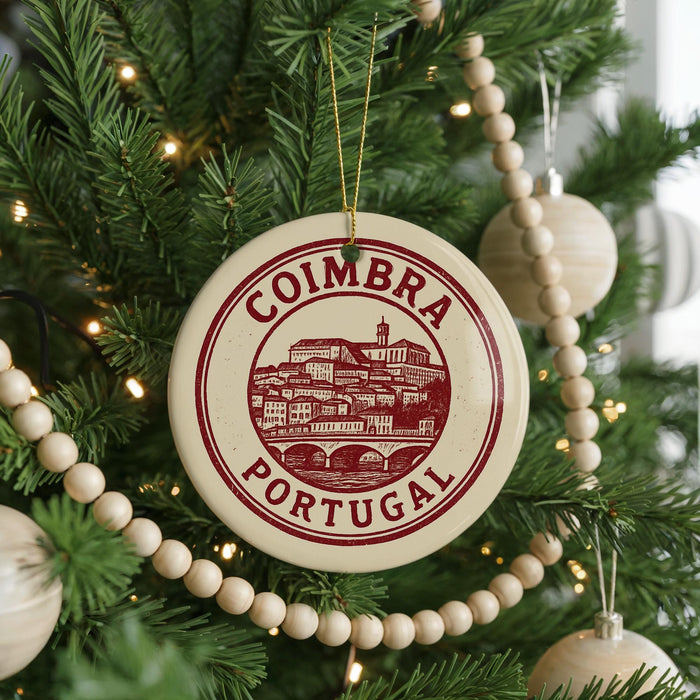 A Christmas tree decorated with ornaments, including a circular ornament with the text "COIMBRA PORTUGAL" on it.