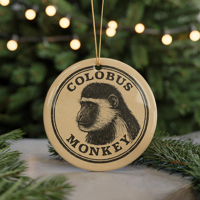 A circular ornament featuring a monochrome illustration of a monkey's face, with the text "COLOBUS MONKEY" printed on it.