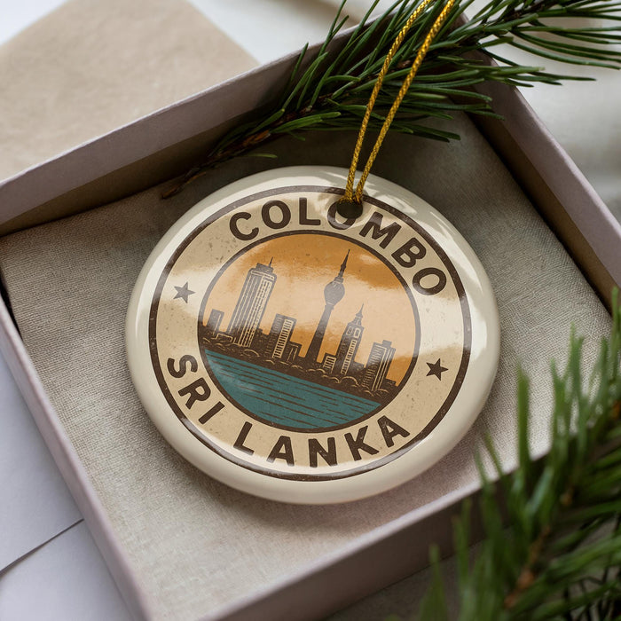 A circular ornament with the text "COLOMBO SRI LANKA" and an illustration of a city skyline, placed in a box with pine branches.