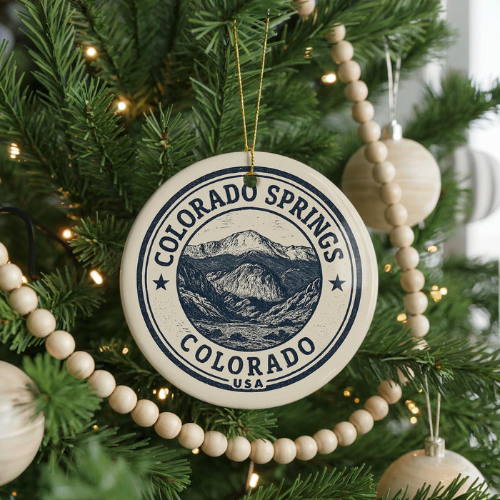 A Christmas tree decorated with ornaments, including a round ornament with the text "COLORADO SPRINGS COLORADO USA" and a beaded ornament.