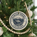 A Christmas tree decorated with ornaments, including a round ornament with the text "COLORADO SPRINGS COLORADO USA" and a beaded ornament.
