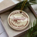 A round ornament with the text "COMMON SQUID" printed on it, surrounded by a pine branch and pine needles.