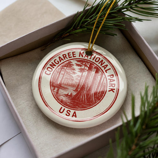 A white ornament with a red border and the text "CONGAREE NATIONAL PARK USA" is displayed in a box, surrounded by pine branches.