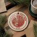 A circular ornament with the text "CONGAREE NATIONAL PARK USA" printed on it, surrounded by pine branches and a cup of coffee on a wooden surface.