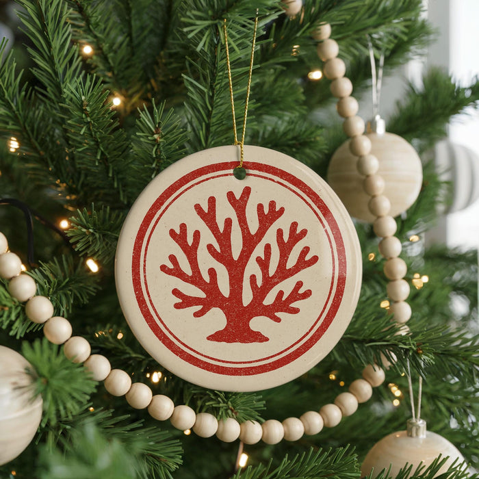 A Christmas tree decorated with ornaments, including a round ornament with a red tree design and a string of wooden beads.