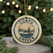 A circular ornament with the text "CORFU GREECE" and an illustration of a lighthouse and a house, hanging from a string.