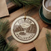 A decorative ornament with the text "CORON PHILIPPINES" and an illustration of a boat on a lake, surrounded by pine branches and a cup of coffee.