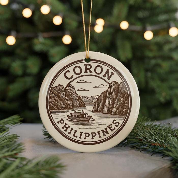 A round ornament with the text "CORON PHILLIPPINES" and an illustration of a boat on a lake, surrounded by mountains, is hanging from a string.