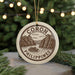 A round ornament with the text "CORON PHILLIPPINES" and an illustration of a boat on a lake, surrounded by mountains, is hanging from a string.