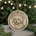A circular ornament featuring a dog's head and the text "COTON DE TULEAR" is displayed in front of a blurred Christmas tree with twinkling lights.
